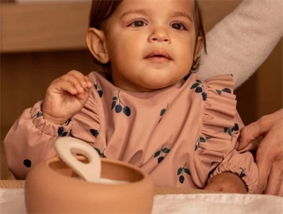 Barn iført Liewood hagesmæk berry / pale tuscany med flæser og lange ærmer