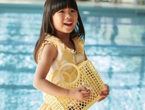 Barn iført Liewood Dove svømmevest i gul nuance ved swimmingpool