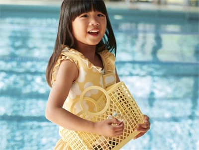 Barn iført Liewood Dove svømmevest i gul nuance ved swimmingpool