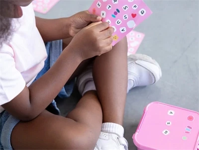 Barn leger med klistermærker og pink MontiiCo snackbox floss