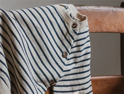 Petit Piao strikcardigan med knapper i siden på en stol